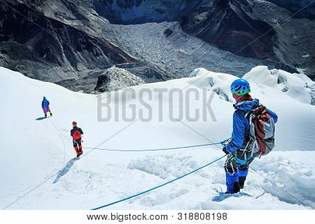 Climber Reaches The Summit Of Mountain Peak Enjoying The Landscape View.