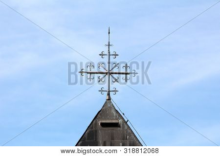 Unusual Shiny Metal Cross On Top Of Old Local Church Roof Surrounded With Lightning Rod And Dilapida