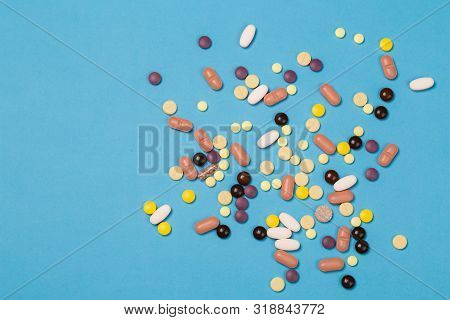 Many Scattered Colorful Medical Pills On Blue Background. Pills Are Scattered Over A Blue Background