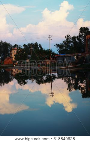 Clear Reflection Of A Small Village In The Water Of A Lake