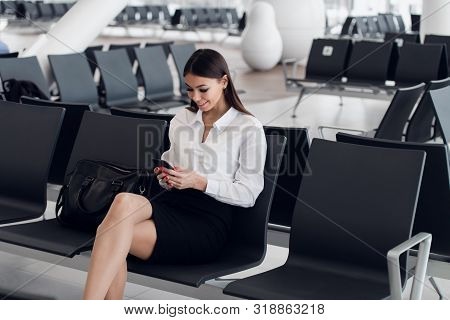 Woman Reading Phone Messages In Airport Waiting Room. Happy Girl Buying E-ticket, Making Hotel Reser