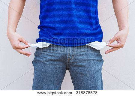 Man Showing His Empty Pockets On Wall Background.