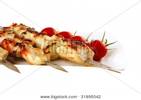 Chicken shish kebab på hvidt fad med grøntsager