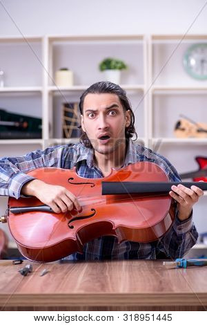 Young handsome repairman repairing cello