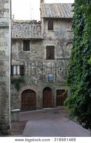 Ancient Tuscan Walled City Houses With Towers And Stone Walls And Paved Cobbled Streets In Italy