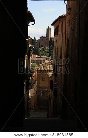 Ancient Tuscan Walled City Houses With Towers And Stone Walls And Paved Cobbled Streets In Italy