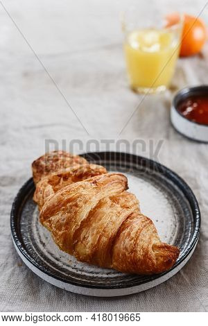 Breakfast With Croissant, Jam, Juice And Tangerine On Greige Linen Tablecloth. Selective Focus