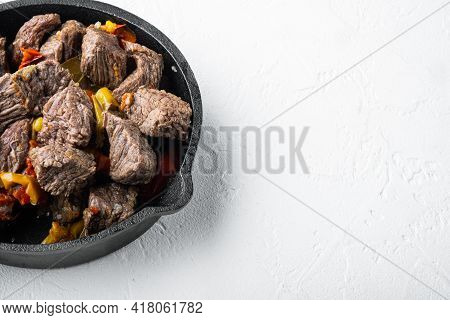 Mongolian Beef, Pieces Of Beef Stewed In Soy Sauce Set, In Cast Iron Frying Pan, On White Stone  Sur