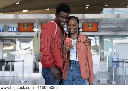 Loving Couple Waiting For Flight In Airport Terminal Hug, Take Selfie Photo On Smartphone. African M