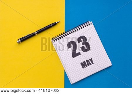 May 23th. Day 23 Of Month, Calendar Date. Notebook With A Spiral And Pen Lies On A Yellow-blue Backg