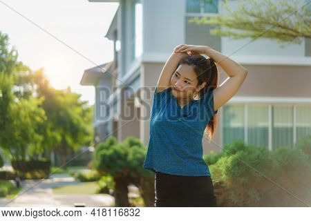Asian Woman Stretching To Warm Up Or Cool Down, Before Or After Exercise, Near The Front Door In The