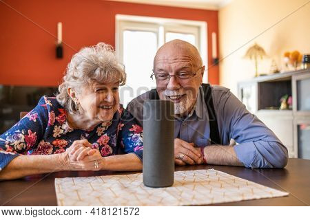 Excited senior couple using a Virtual Assistant at home
