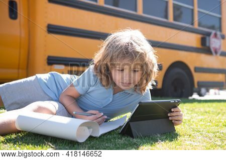 Pupil Writing Homework On Grass With Laptop Outdoor Near School Bus. Distance Learning Online Educat