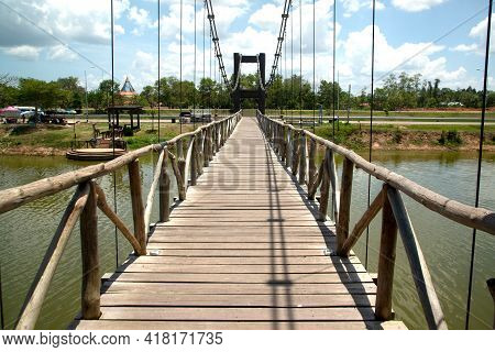 Wooden Suspension Bridge That Crosses A Reservoir In A Public Park In Thailand.
