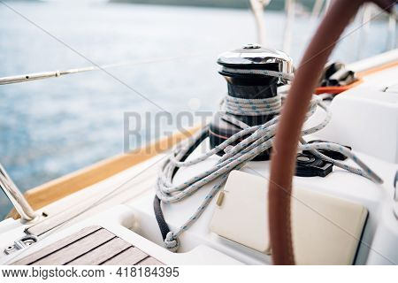 Black Halyard Winch With A White Cable Coiled Around Against The Background Of The Bow Of Sailboat
