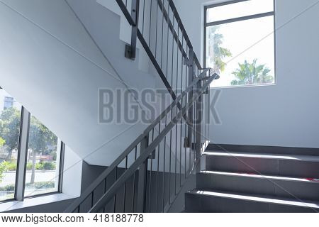Stairs lit by daylight from windows on landing of staircase in mid 20th century building. architecture and practical interior design.