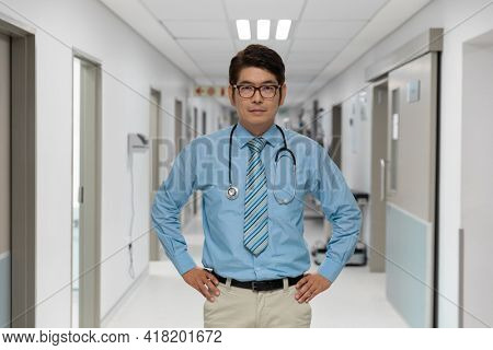 Portrait of mixed race male doctor standing in hospital corridor. medicine, health and healthcare services.
