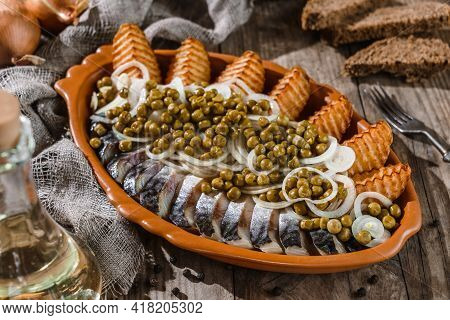 Fried Potatoes With Herring Fish Slices, Canned Green Peas And Onions In Plate On Wooden Rustic Tabl
