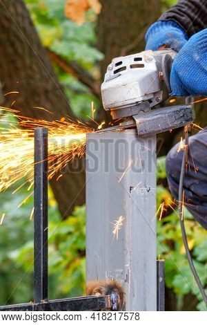 The Hands Of The Worker Cut And Level The Metal Post With An Angle Grinder, Hot Sparks Fly Out Durin
