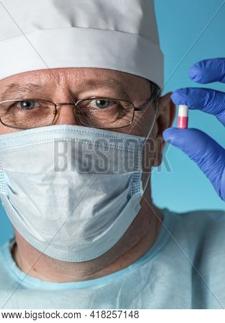 A Doctor In Medical Clothing: A Cap, Gloves, Dressing Gown And Mask, Glasses. He Holds A Medicine Ca