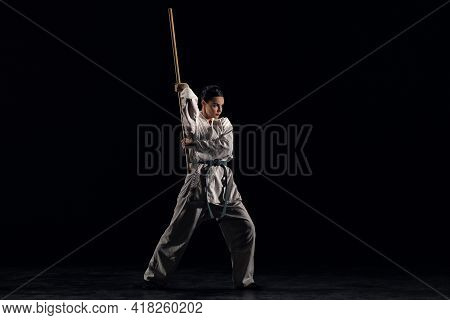 Young Woman In Kimono Practicing With Jodo On A Black Background