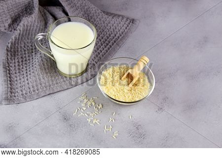 Rice Milk In A Glass Mug And A Rice Grains In A Bowl On A Grey Background. Vegetable Milk. Vegan Lac