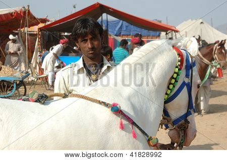 Joven indio gitano nómada con White Horse Pushkar Camel Feria, India