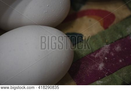 Two Whole White Eggs Set Out On A Quilted Place Mat