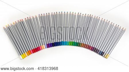Set Of Colored Wooden Pencils Painted Gray Laid Out In A Semi-fan On A White Background, Top View