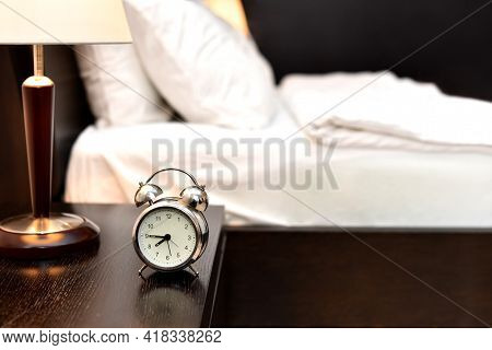 Alarm Clock Next To Bed In Bedroom Without People. Made Bed Early In Morning In Hotel Room Or At Hom