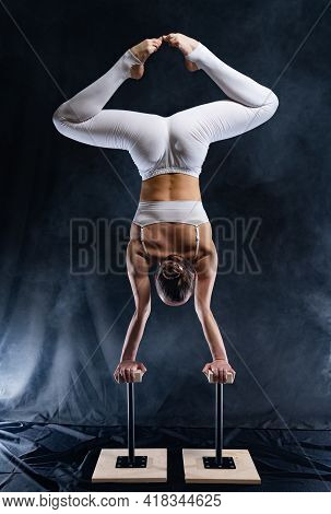 Flexible Circus Artist - Female Acrobat Doing Handstand On The Back And Smoker Background. Concept O