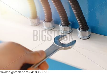 These Are Power Cables In Corrugated Insulation And A Rock Electrician With A Wrench Close Up Agains