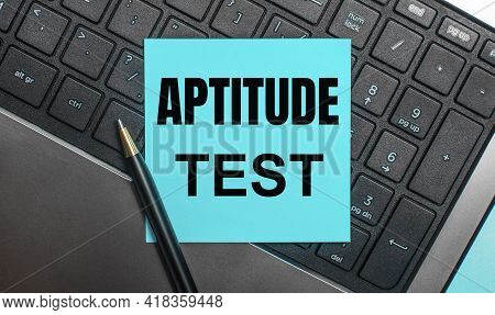 The Computer Keyboard Has A Pen And A Blue Sticker With The Text Aptitude Test. Flat Lay.