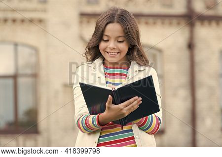 Little Girl Hold Book. Girl With Book School Building Background. Book From Library. Making Notes. I