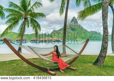 Vacation - Elegant woman relaxing in hammock on Bora Bora travel paradise during summer holidays in tropical Bora Bora, French Polynesia, Tahiti. Luxury overwater bungalow resort hotel. Travel icon