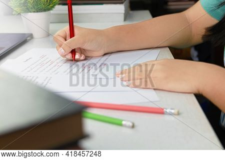 Hand Holding Red Pen Over Proofreading Paper On White Table