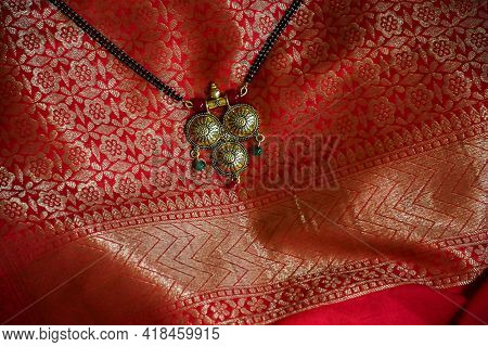 Stock Photo Of Beautiful Fancy Golden Mangalsutra With Black Pearl Chain On Beautiful Red And Golden