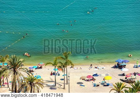 MENTON, FRANCE - JULY 31, 2020: People on the public beach on sunny summer day in Menton - small town on Mediterranean sea,  famous travel destination and tourist resort on French Riviera.