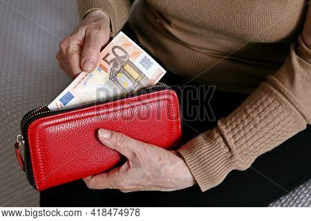 Elderly Woman Takes Out A Euro Note From Her Wallet. Concept Of Pension Payments, Savings At Retirem