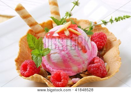 Rosa gelato sundae con mandorla, sciroppo rosso e lamponi freschi con erbe