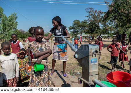 Mzuzu, Malawi. 30-05-2018. One Black Woman Is Helping Another One To Lift A Heave Bucket Of Water To