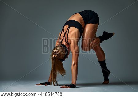 Beautiful And Athletic Girl In A Top And Shorts And Black Socks Posing In Studia On A Gray Backgroun