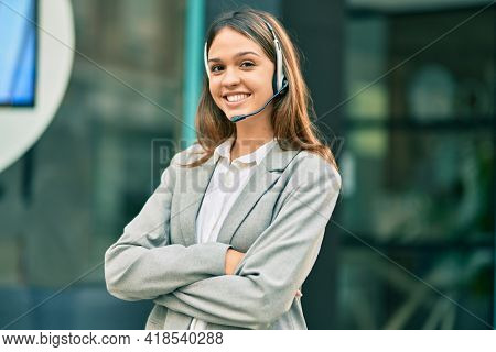Young latin call center aget girl smiling happy using headset at the city.