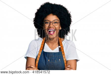 Young african american woman dressmaker designer wearing atelier apron smiling and laughing hard out loud because funny crazy joke. 