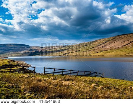 A Wooden Fence Goes Down To A Reservoir With Mountains And Billowing Clouds. Scar House Reservoir. N