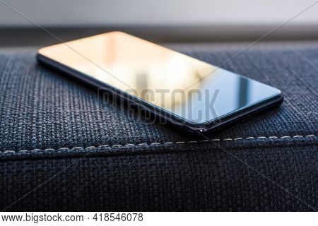 Business Smartphone With Reflection Lying On The Armrest Of A Couch