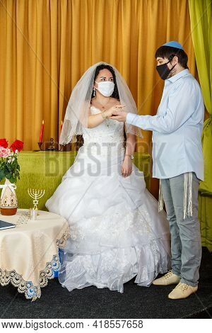During A Chuppah Ceremony At A Jewish Wedding In A Synagogue, The Groom Puts A Ring On The Bride's I
