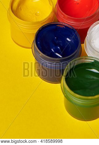 Multicolored Cans Of Paint On A Yellow Background