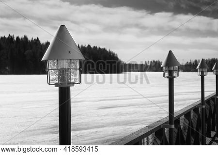 Lanterns Atteched To A Wooden Pier By A Frozen Lake. The Weather Is Quite Nice On This Spring Day.
