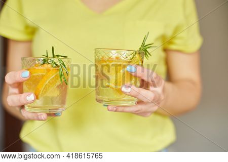 Female Woman Hand Hold Two Glasses Of Citrus Orange And Rosemary Fresh Lemonade
